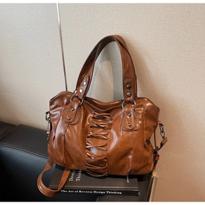 Detail of vintage brown tote bag featuring lace-up design and silver rivet hardware