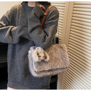 Dettaglio borsa tote in peluche kaki con tracolla a catena e ciondolo a forma di coniglio