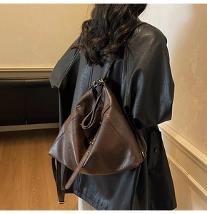 Detail of dark brown leather backpack showing smooth texture and bronze hardware on back