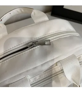 Close-up of smooth silver metal zipper and hardware on white canvas shoulder bag