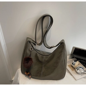 Detail of olive green hobo bag with contrast stitching and decorative plush pendant