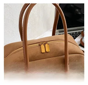 Detail of gold-tone dual zippers on brown lychee-textured leather pillow handbag