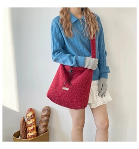 Detail of red plush tote bag with furry texture and central woven rectangular label