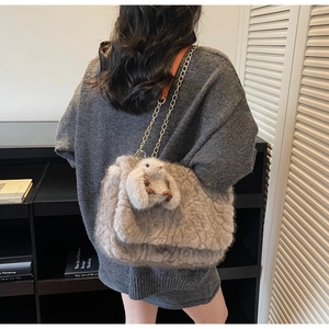 Dettaglio della borsa tote taupe in peluche con ciondolo a coniglio e tracolla in metallo