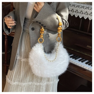 Détail d'un sac demi-lune en fausse fourrure blanche avec poignée en perles de bois