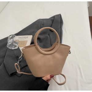 Dettaglio della borsa a secchiello beige con manico circolare e tracolla rimovibile