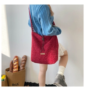 Detail of red plush tote bag featuring a leather label and drawstring closure