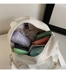 Detail view of the spacious interior of a white canvas crossbody bag with daily essentials