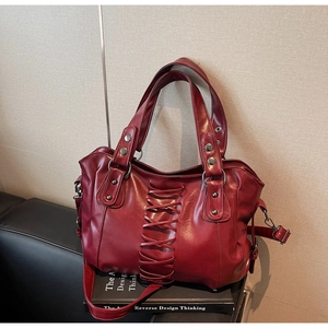 Detailed close-up of the vintage dark red leather tote featuring corset-style lacing and rivets