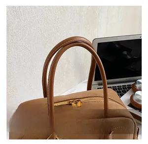 Close-up of brown pillow bag with gold double zippers and dual cylindrical handles