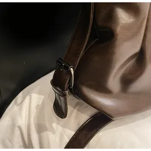 Détail d'un sac à bandoulière marron foncé avec ferrures brillantes et texture cuir