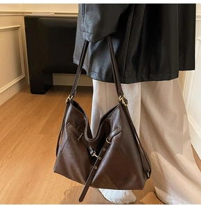 Detail of dark brown leather tote bag with vintage gold buckle on a shoulder strap