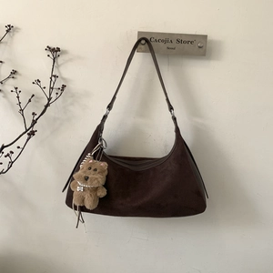 Detail of a dark brown suede crescent bag with a cute plush bear charm with pearls