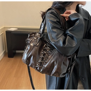 Detail of dark brown corset-style tote with rivet studs and lace-up strap on model side view