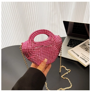 Dettaglio della borsa in acrilico rosa metallizzato con trama intrecciata e catena dorata