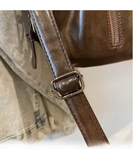 Détail de la bandoulière réglable avec boucle en métal sur un grand sac marron vintage