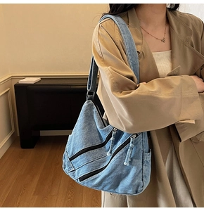 Détail d'un sac bandoulière en denim bleu avec plusieurs zips et sangle réglable