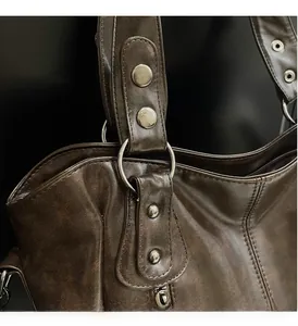 Détail d'un sac cabas en cuir marron vintage avec garnitures argentées et coutures