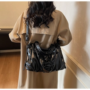 Close-up of black punk tote bag featuring criss-cross lace-up details and glossy leather