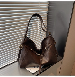 Close-up of vintage dark brown faux leather tote with metallic buckle and natural light shadow