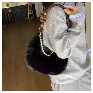 Détail d'un sac bandoulière en fausse fourrure noire avec poignée en perles de bois