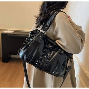 Detail of glossy black tote bag with corset-style lace-up sides and silver rivet accents