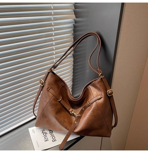 Detail of adjustable gold buckle and rich brown faux leather texture on tote bag