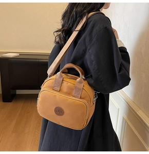 Close-up of ginger yellow crossbody bag with adjustable wide strap and round logo patch
