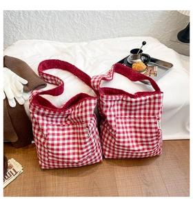 Detail of red gingham tote bag featuring cozy fleece lining and external pocket design
