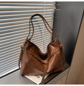 Detailed view of dark brown leather tote bag with adjustable straps and metal buckles