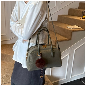 Detail view of olive green leather pillow bag with brown fur ball and gold zipper