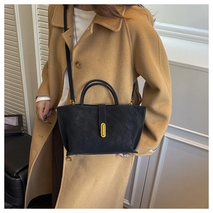 Detail of black tote bag featuring matte leather texture and elegant gold metal buckle