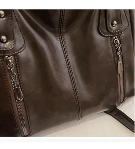 Gros plan du sac en cuir vintage marron foncé avec rivets et doubles fermetures éclair
