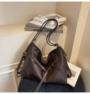Detail of coffee brown tote bag with vintage gold buckle and smooth leather texture