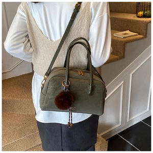 Detail of army green pillow bag with golden hardware and fuzzy charm accessory