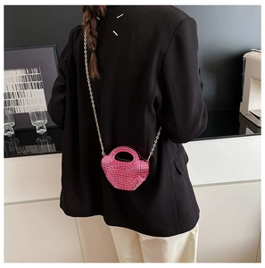 Mini borsa rosa shocking con catena dorata indossata da modella con giacca