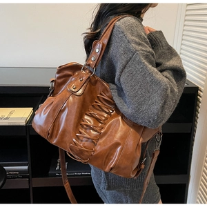 Detail of a large brown faux leather tote with decorative lacing and wide shoulder strap