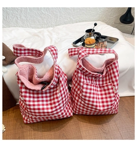 Detail of red gingham tote bag with soft pink faux fur lining and plush texture