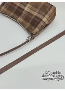 Detail of adjustable brown strap and texture on vintage plaid shoulder bag