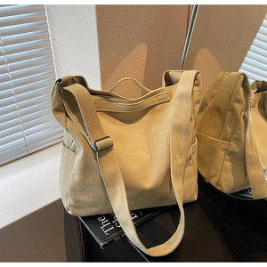 Detailed view of khaki canvas tote bag with wide shoulder strap and side pocket