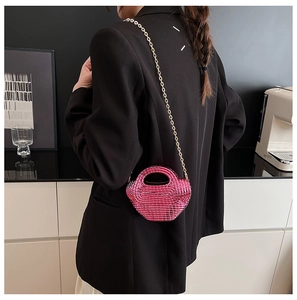 Dettaglio borsa a catena in acrilico rosa fucsia con tracolla dorata su modella alla moda