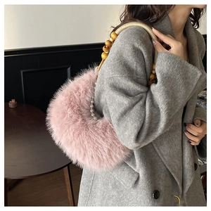 Détail d'un sac à main rose en peluche avec perles en bois et poignée élégante en perles