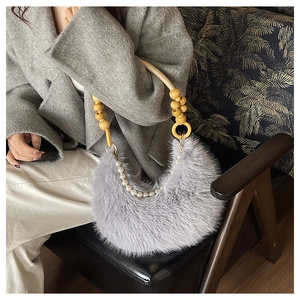 Détail du sac croissant en fausse fourrure grise avec chaîne perlée et anse en bois