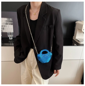 Dettaglio della mini borsa in strass blu con tracolla dorata su un outfit con blazer