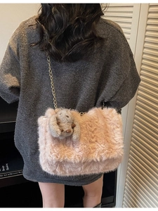 Borsa tote in peluche rosa con catena dorata e ciondolo a coniglio su modella