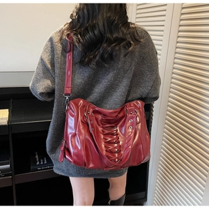 Detail of dark red faux leather tote bag with silver metal rings and rivet accents