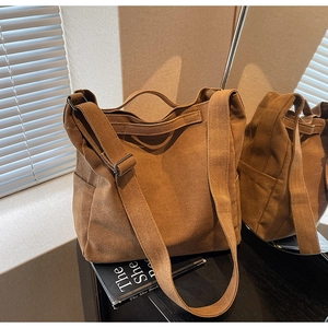 Detail view of large canvas tote bag in brown with wide shoulder strap and side pocket