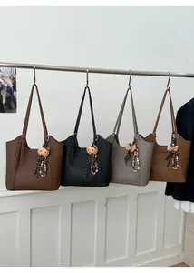 Détail de quatre grands sacs cabas en cuir marron, noir et gris avec breloques mignonnes