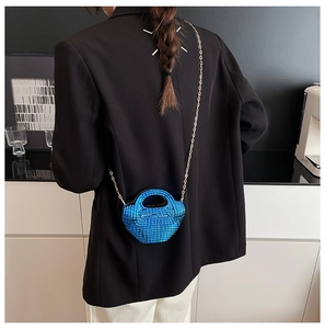 Dettaglio della borsa a tracolla con perline blu brillante e catena dorata su una modella