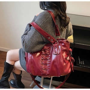 Detail of dark red punk tote bag featuring decorative lacing and glossy PU leather texture